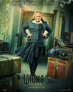 Woman in elegant green Victorian gown with ruffled skirt standing in luxurious room with vintage suitcases