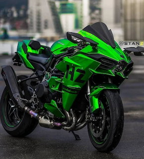 Green Kawasaki H2 superbike parked on pavement with buildings in the background