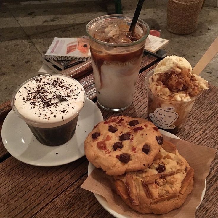 Overhead flatlay of coffee cups, iced drinks, and chocolate chip cookies on a wooden table