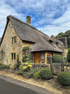 Stone cottage with thatched roof and garden in English countryside