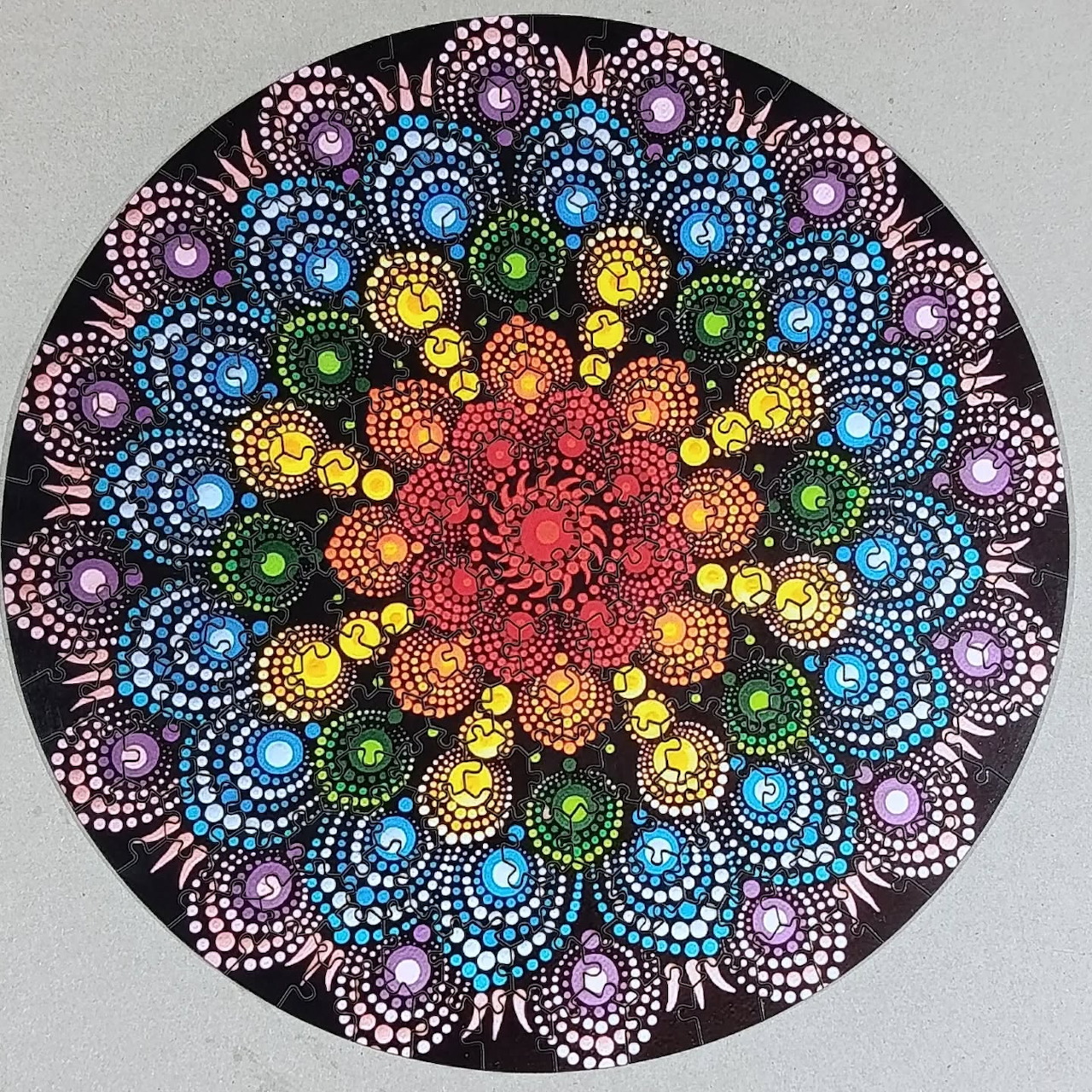 Colorful circular mandala made of dotted floral patterns on a dark background