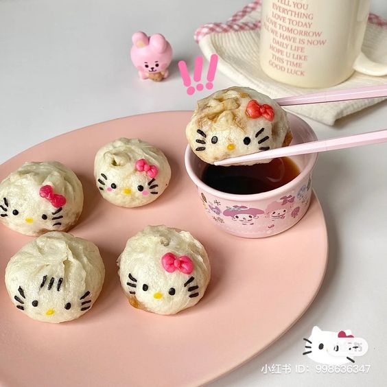 Hello Kitty shaped steamed dumplings on a pink plate with soy sauce and chopsticks