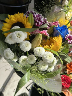 Bright bouquet with sunflowers, white mums, and purple flowers in sunlight