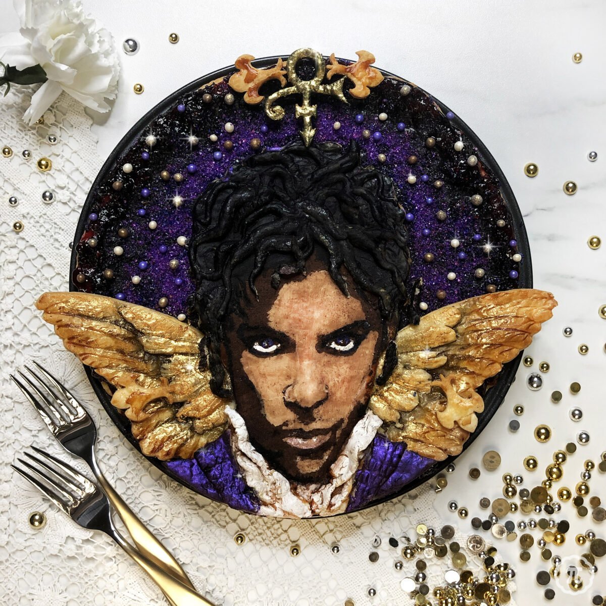 Food art portrait of Prince created with pie crusts shaped as wings and hair, berries forming facial features on decorative plate