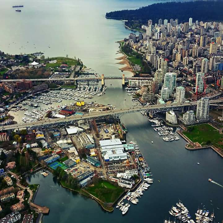 Aerial view of Granville Island marina, bridges, boats, and a dense waterfront city skyline
