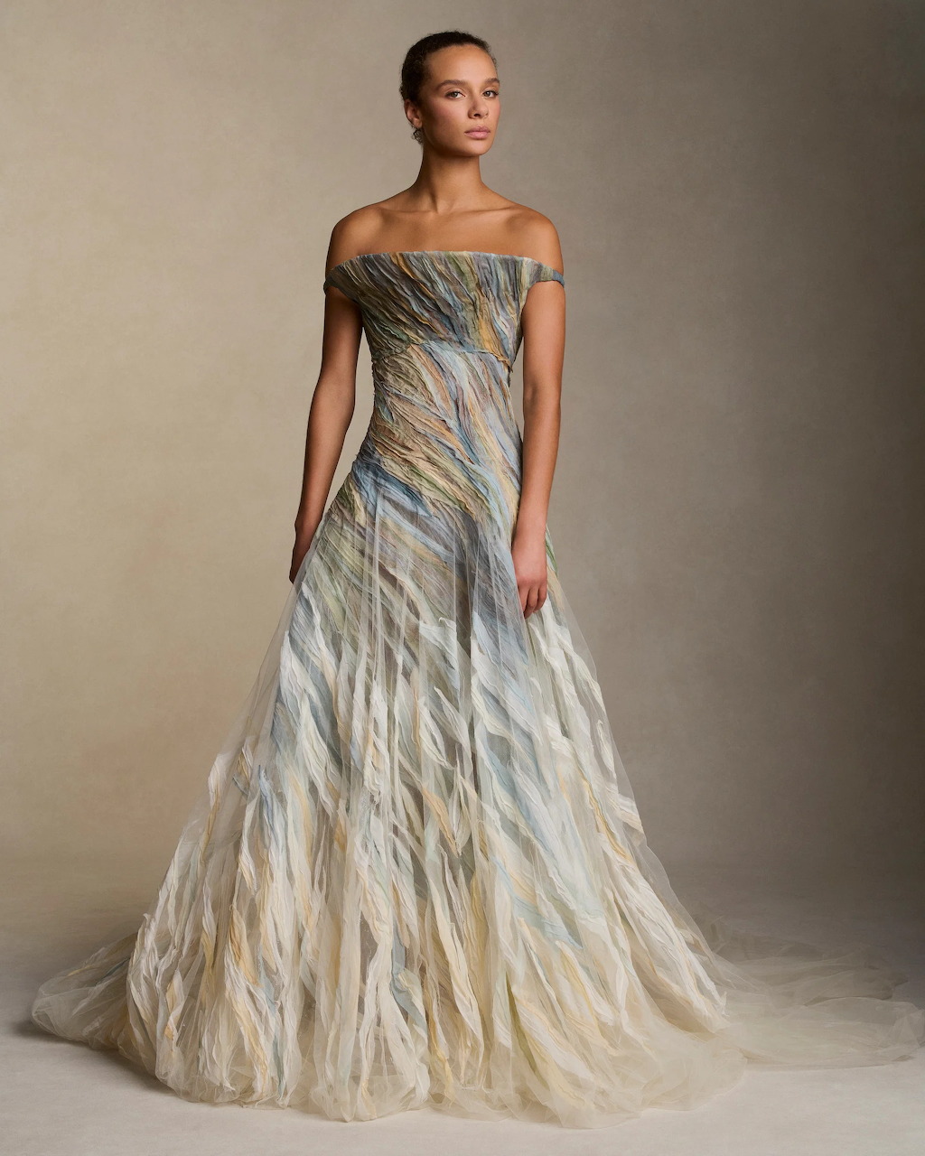 Model in an off-the-shoulder feathered bridal gown in blue and gold tones