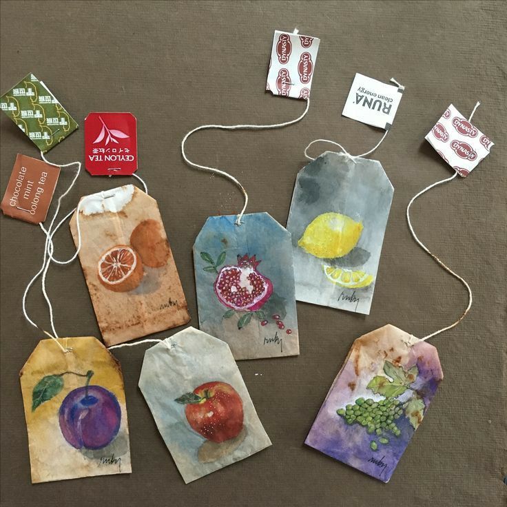 Watercolor tea bag illustrations with fruit and flower designs on a brown surface