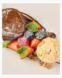 Chocolate crepe with fresh fruit filling, dusted with powdered sugar, served with vanilla ice cream and nuts