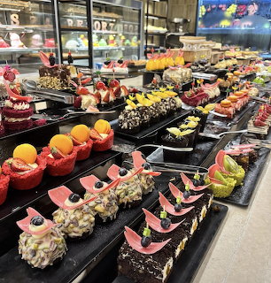 Dessert buffet table with assorted cakes, pastries, and fruit-topped sweets on black trays