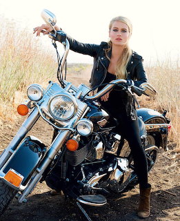Woman in leather jacket posing on vintage motorcycle outdoors