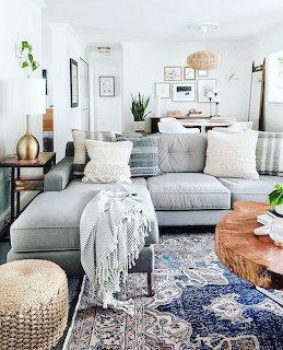 Bright living room with gray sectional sofa, blue patterned rug, wood coffee table, and neutral decor