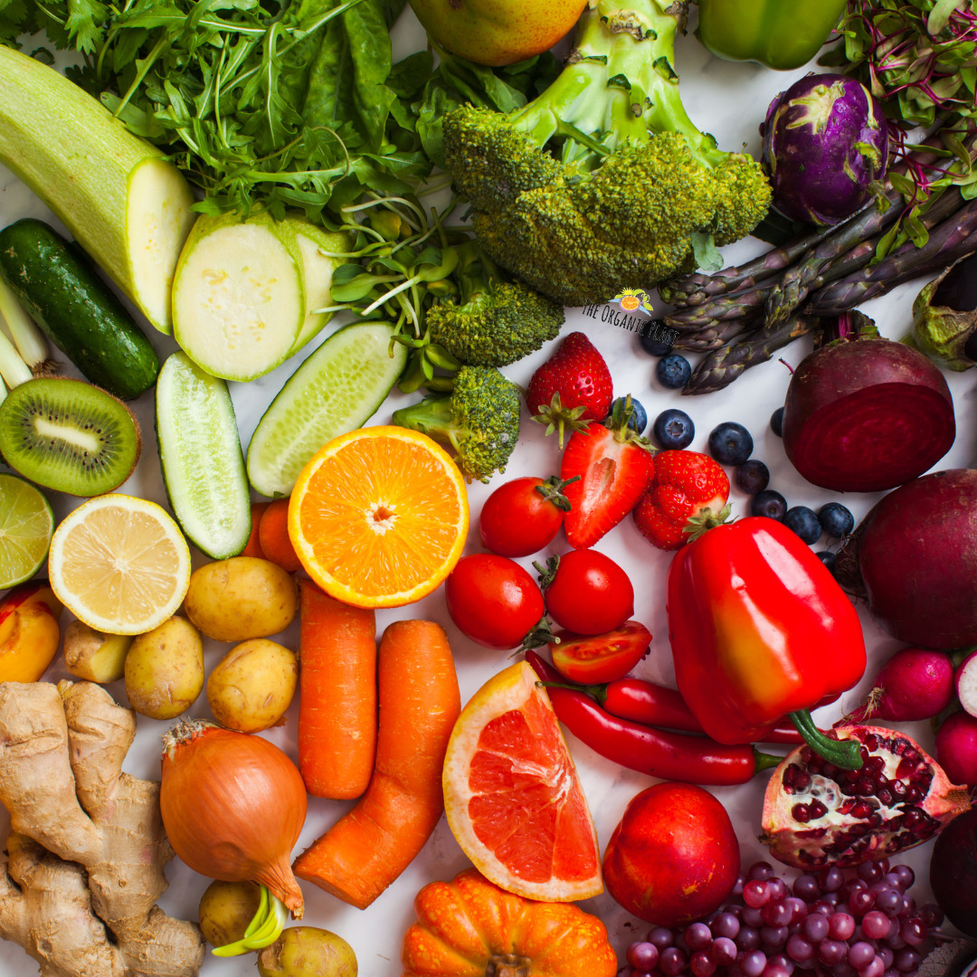 Vibrant collection of fresh fruits and vegetables including peppers, tomatoes, citrus, berries, greens, and root vegetables