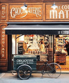 French chocolaterie storefront with vintage wooden signage, display windows, and a delivery tricycle cart