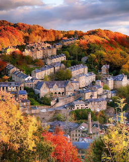 Hillside village with stone houses among autumn trees in warm colors under cloudy sky
