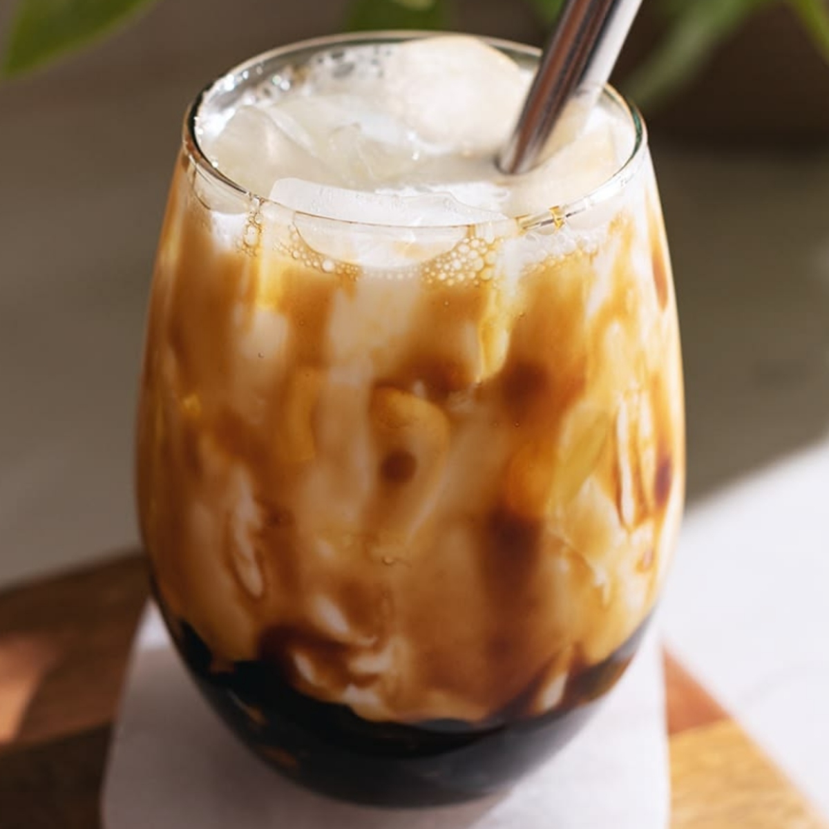 Glass of iced boba milk tea with tapioca pearls and straw on wooden surface