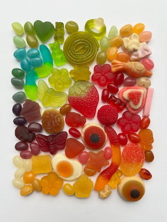 Colorful candy arrangement organized by rainbow colors including gummy bears, rings, and fruit-shaped sweets