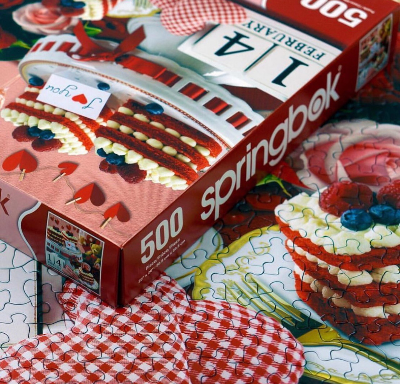Cake puzzle box with loose pieces beside layered strawberry cake slices