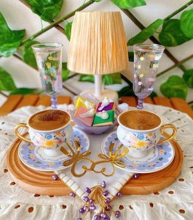 Two decorative cups of Turkish coffee on a wooden tray with water glasses, lamp, and Turkish delight