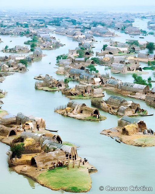Aerial view of traditional reed houses on small islands in a vast marshland waterway system