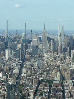 Aerial photograph of Manhattan skyline showing dense urban skyscrapers and buildings under clear sky