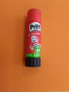 Red Pritt glue stick on an orange background