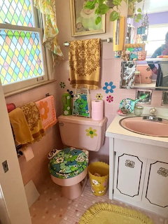 Vintage pink bathroom with matching toilet, sink, patterned towels, stained glass window, and floral decor