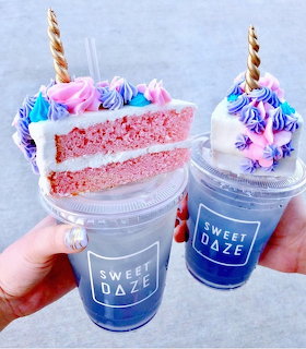Two milkshakes with cake slices, whipped cream, and candy toppings in Sweet Daze branded cups