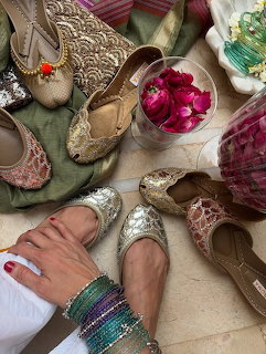 Decorative embroidered ethnic flat shoes with a hand in colorful bangles and rose petals