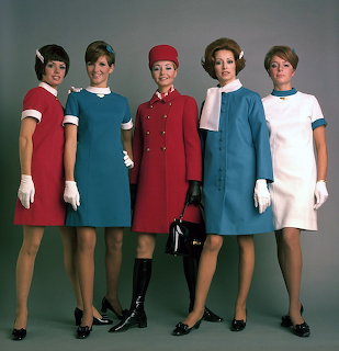 Five women in colorful vintage airline uniforms posing in a studio
