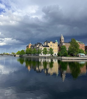 Historic Swedish city buildings reflected in calm water under dramatic cloudy sky