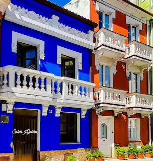Bright blue and orange Mediterranean houses with white decorative balconies and green shutters
