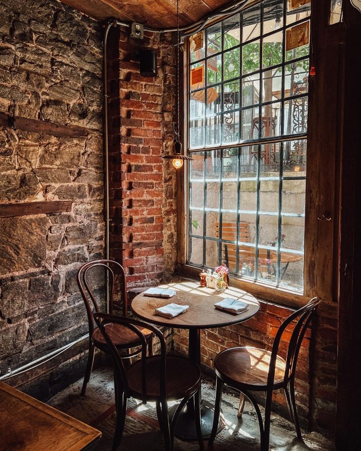 Cozy cafe corner with brick walls, round wooden table, bentwood chairs, and large window