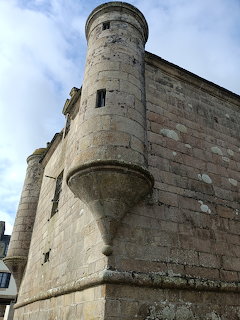 Medieval stone tower with cylindrical turret and weathered walls under blue sky