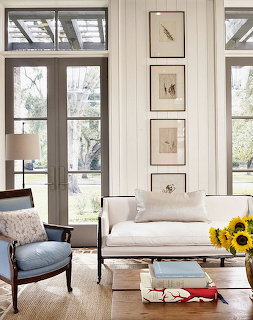 Bright white shiplap living room with French doors, white sofa, blue armchair, and sunflowers on coffee table