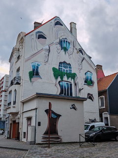 White corner building with sureal street art murals around windows in Boulogne sur Mer, France