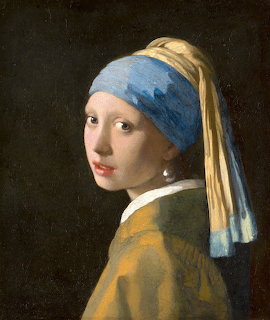 Portrait of a young woman in blue turban and pearl earring looking over her shoulder against dark background