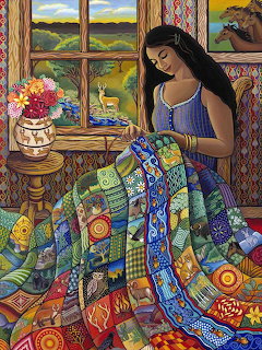 Woman in blue top sewing a colorful patchwork quilt at a table by a window overlooking rolling hills