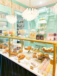 Elegant pastel green bakery interior with glass display case filled with pastries and macarons