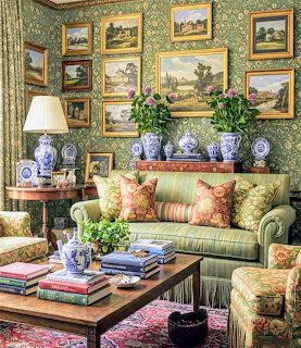 Ornate living room with green patterned walls, multiple framed paintings, striped sofa, and coffee table with books