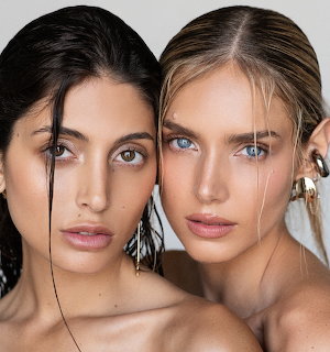 Close-up portrait of two women with natural makeup and jewelry looking at camera