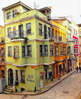 Brightly painted yellow, orange and pink townhouses on a narrow cobblestone street corner