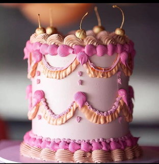 Pink frosted layer cake with piped decorations and bows on top