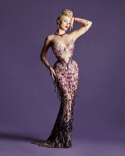 Woman posing in ornate beaded evening gown on purple background