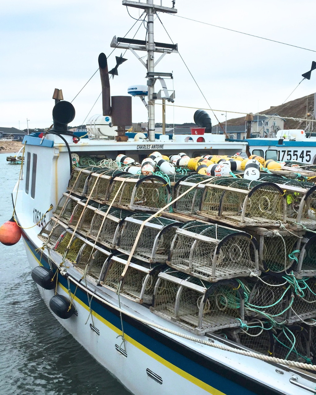 Fishing boat at a harbor loaded with stacked metal traps and ropes on deck