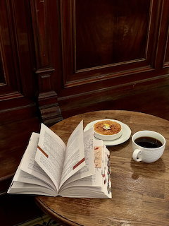 Open book on table with coffee and dessert in café