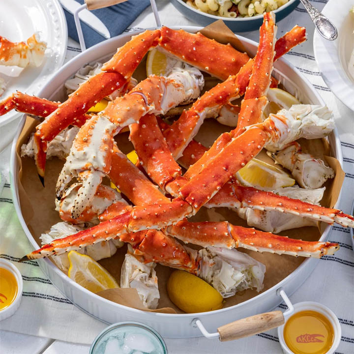 Cooked crab legs in a white pot with lemon wedges on a table