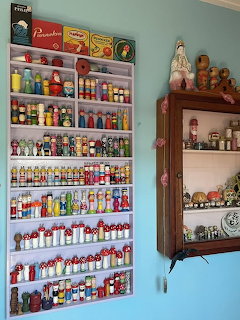 Shelves on a blue wall filled with colorful vintage figurines and small containers