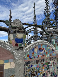 Colorful mosaic sculptures and metal spires at Watts Towers with blue sky background
