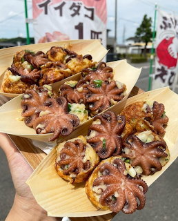 Takoyaki octopus balls on wooden serving trays with toppings and sauce
