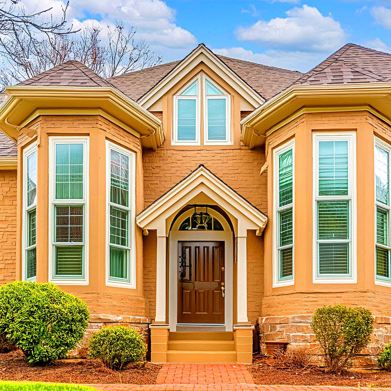 Orange brick two-story house with white-trimmed windows, green shutters, and arched entrance